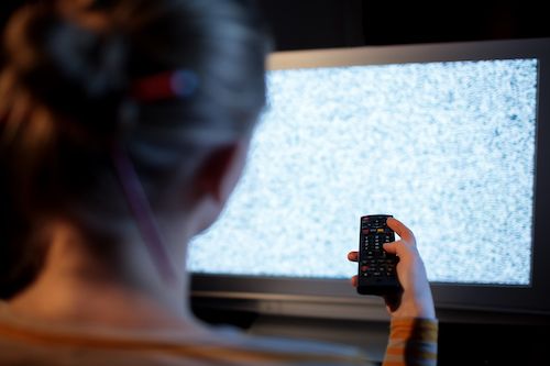 Woman in front of TV experiencing interference