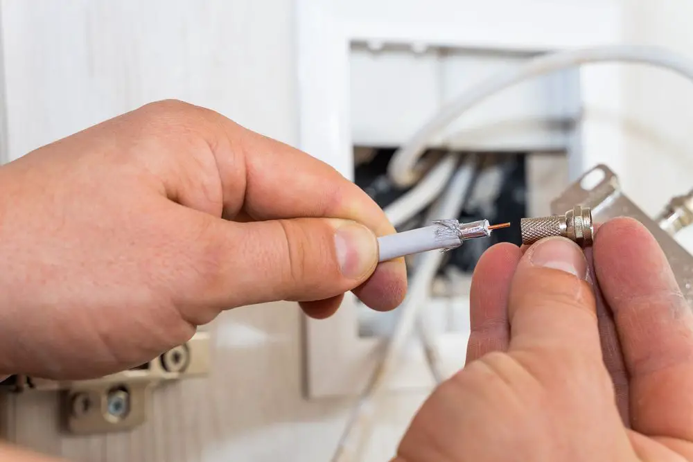 Man placing F-connector on tip of coaxial cable