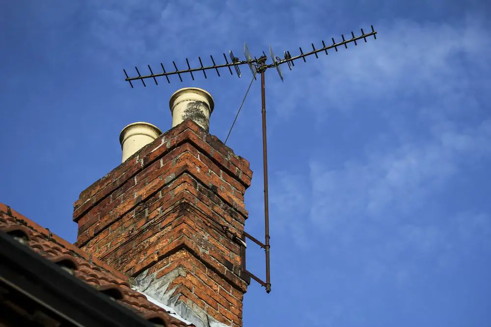 two tv antennas mounted on a rooftop chimney