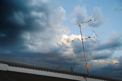 TV antenna on roof against dark sky